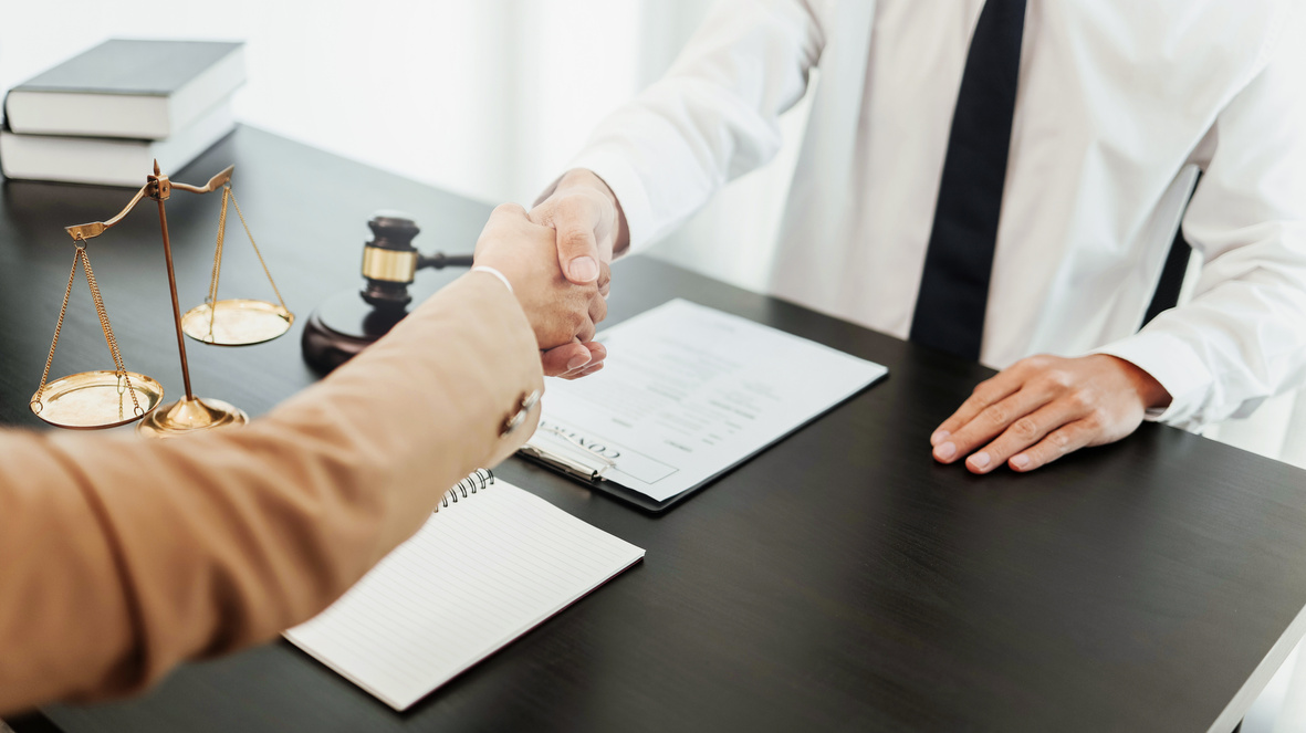 Lawyer consultant shaking hand with client in law firm.